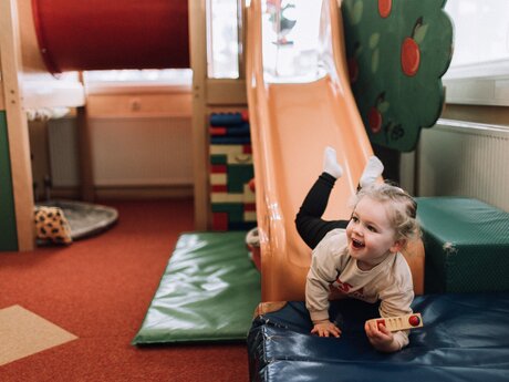 Kleines Mädchen rutscht lachend die Rutsche hinunter in Bertas Kindergarten | © Skischule Fiss-Ladis | Maria Knoll