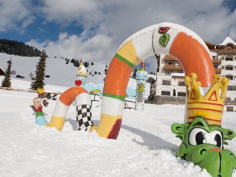 Schneespielplatz mit buntem, schlangenförmigem Hindernis und Burgtürmen im Hintergrund in Serfaus | © Serfaus-Fiss-Ladis Marketing GmbH | Andreas Kirschner