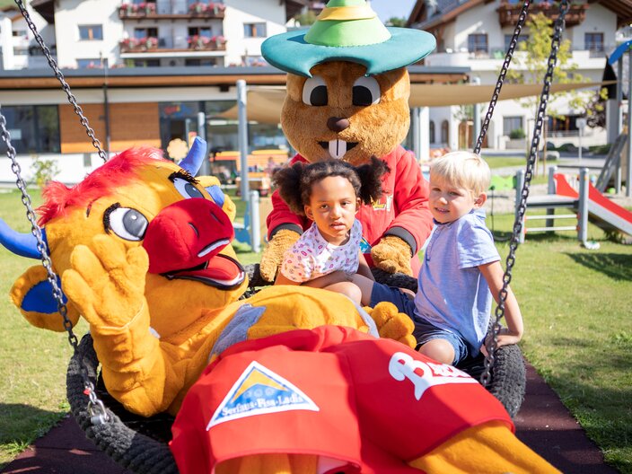 Murmli und Berta im Kinderclub mit Kindern auf Schaukel in Serfaus-Fiss-Ladis, Tirol Österreich | © Serfaus-fiss-Ladis Marketing GmbH | Andreas Kirschner