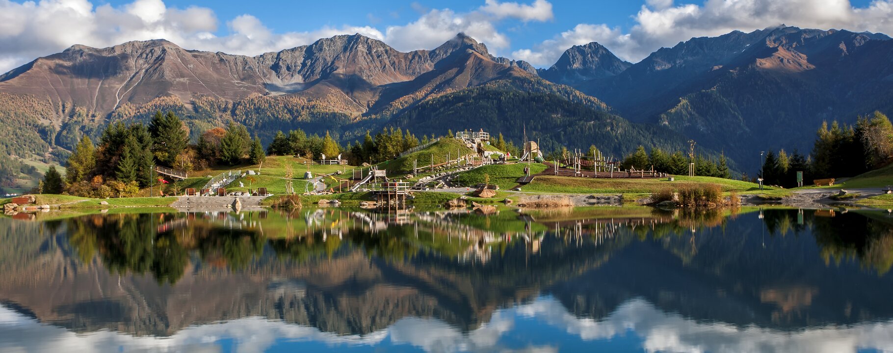 Klarer Wolfsee in Fiss mit Spiegelung der umliegenden Berge und herbstlicher Naturkulisse | © Serfaus-Fiss-Ladis Marketing GmbH | Andreas Kirschner