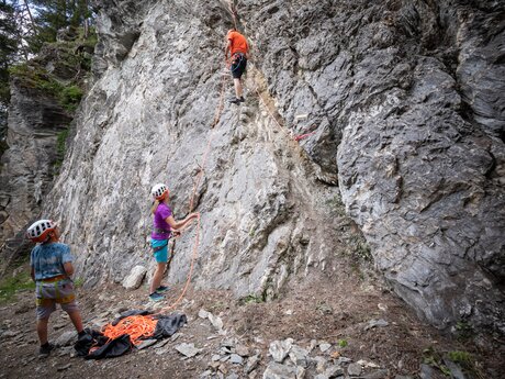 Kind klettert gesichert eine Felswand hinauf, Eltern sichern in Serfaus-Fiss-Ladis | © Serfaus-Fiss-Ladis Marketing GmbH | Andreas Kirschner