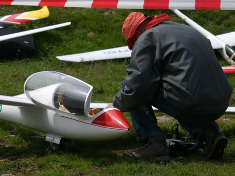 Person mit roter Mütze und Jacke bereitet ein Modellflugzeug auf einer Wiese in Serfaus-Fiss-Ladis vor | © Serfaus-Fiss-Ladis Marketing GmbH