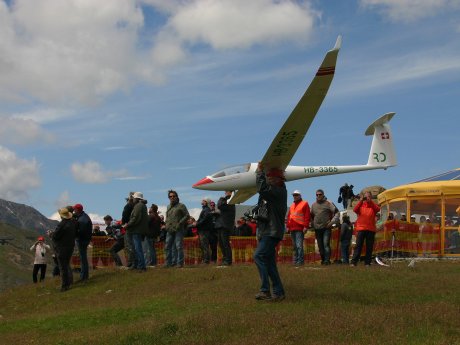 Mann hält großes weißes Modellflugzeug auf einer Wiese in Serfaus-Fiss-Ladis, im Hintergrund Zuschauer und ein gelbes Zelt | © Serfaus-Fiss-Ladis Marketing GmbH