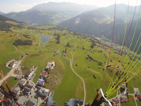 Aus der Vogelperspektive beim Paragleiten über Serfaus-Fiss-Ladis, Blick auf Felder, Wege und umliegende Berge | © Serfaus-Fiss-Ladis Marketing GmbH