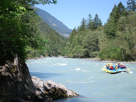 Group rafting on a turquoise river in Tyrol, surrounded by dense forests and mountains | © whynot-tirol.com