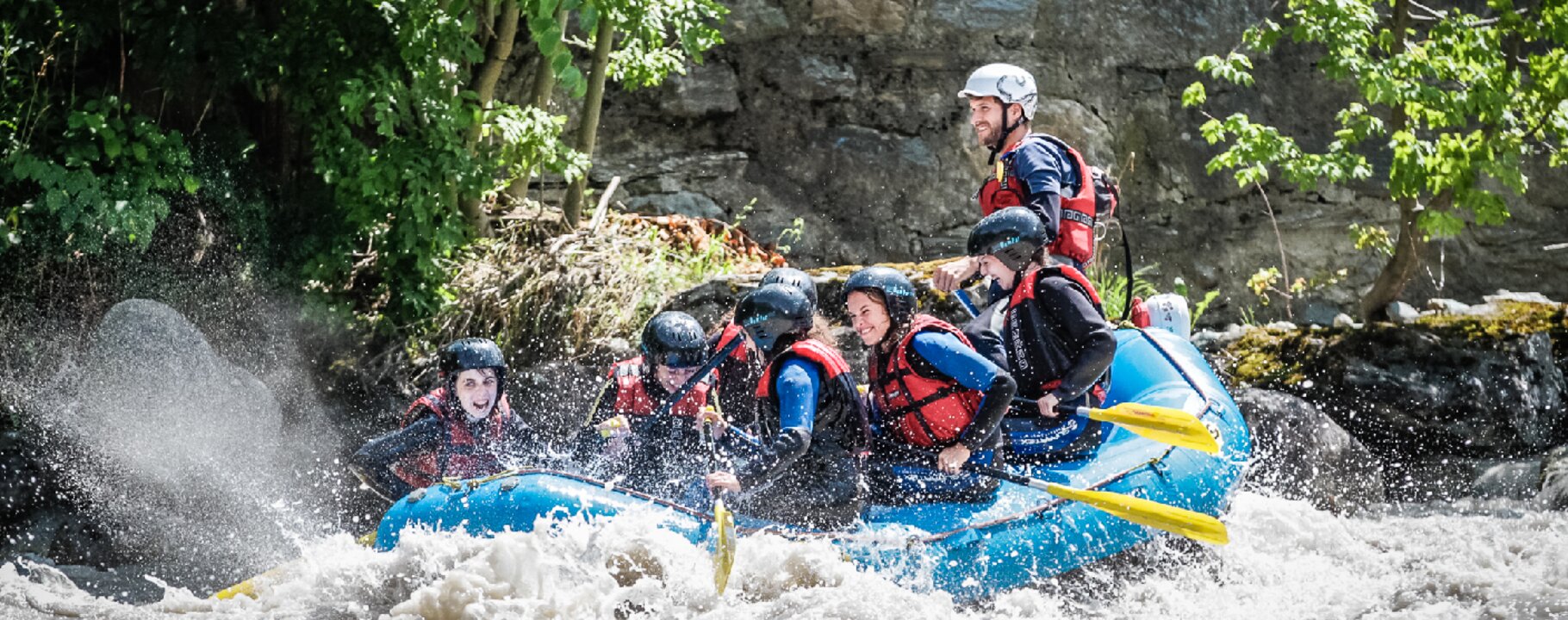 Gruppe mit Helmen und Schwimmwesten beim Rafting in einem aufspritzenden Wildwasserfluss | © whynot-tirol.com