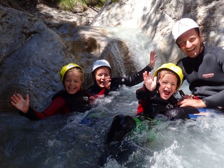 Kinder und Guide beim Canyoning in einem Bach in Serfaus-Fiss-Ladis, alle tragen Neoprenanzug und Helm | © whynot-tirol.com