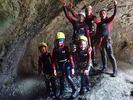 Gruppe mit Kindern und Erwachsenen beim Canyoning in einer Höhle in Serfaus-Fiss-Ladis, alle in Neoprenanzügen und Helmen | © whynot-tirol.com