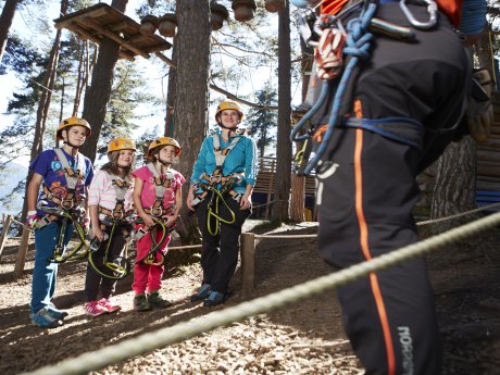 Kinder und Erwachsene mit Sicherheitsausrüstung im Hochseilgarten in Serfaus-Fiss-Ladis | © christianwaldegger.com