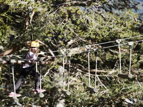 Mädchen mit Kletterausrüstung balanciert auf Hängebrücke im Waldseilpark X-Trees Serfaus | © christianwaldegger.com