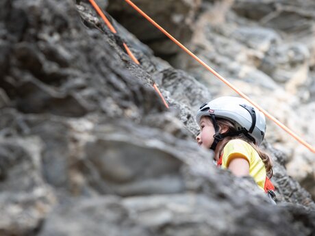 Mädchen mit Kletterhelm an einer Felswand in Serfaus-Fiss-Ladis beim Klettern | © Serfaus-Fiss-Ladis Marketing GmbH | Andreas Kirschner