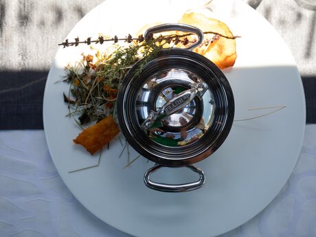 Kunstvoll angerichtetes Gericht mit dekorativen Kräutern und kleiner Edelstahldose auf einem weißen Teller | © Serfaus-Fiss-Ladis Marketing GmbH | Andreas Kirschner