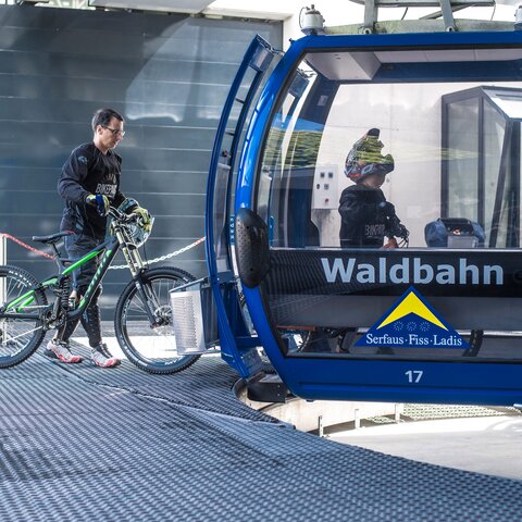 Ein Mountainbiker schiebt sein Fahrrad in eine blaue Waldbahn-Gondel in Serfaus-Fiss-Ladis | © Serfaus-Fiss-Ladis Marketing GmbH