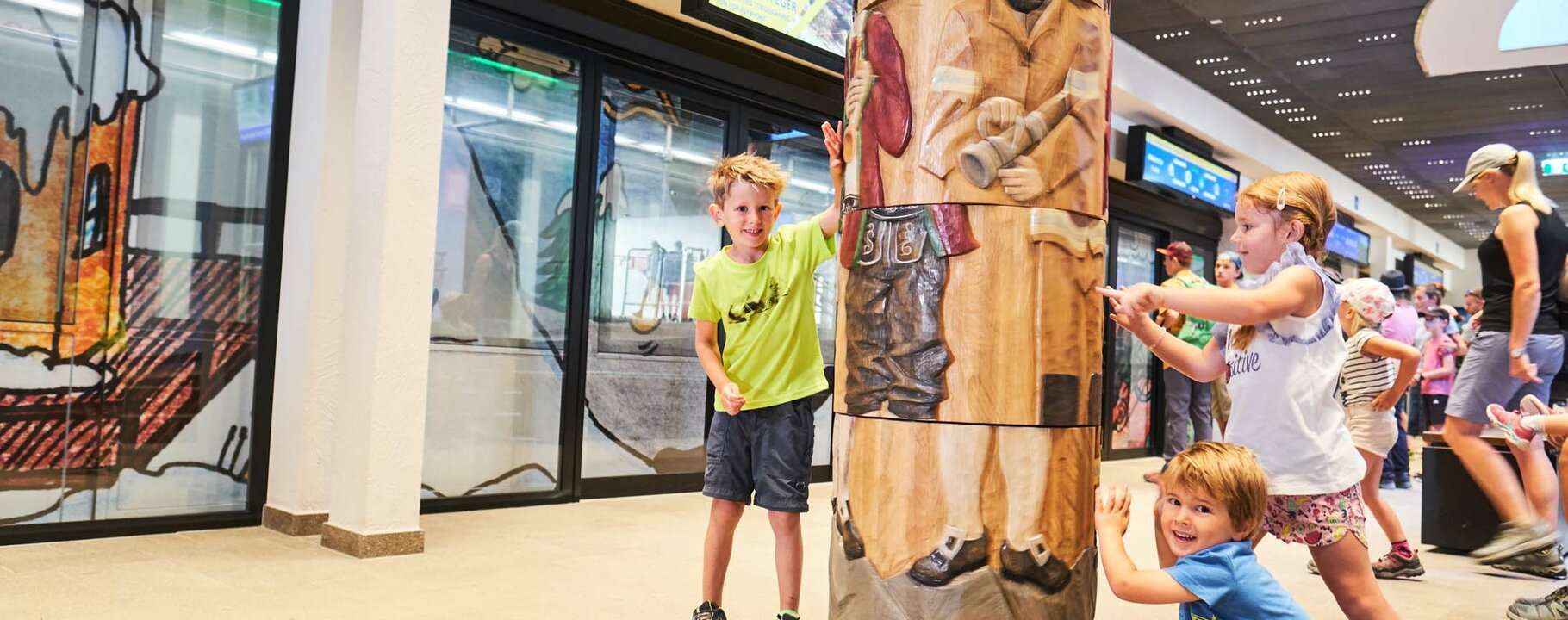 Kinder drehen an einem großen Holzpuzzle mit einem geschnitzten traditionellen Motiv in einer überdachten Freizeithalle | © Serfaus-Fiss-Ladis Marketing GmbH