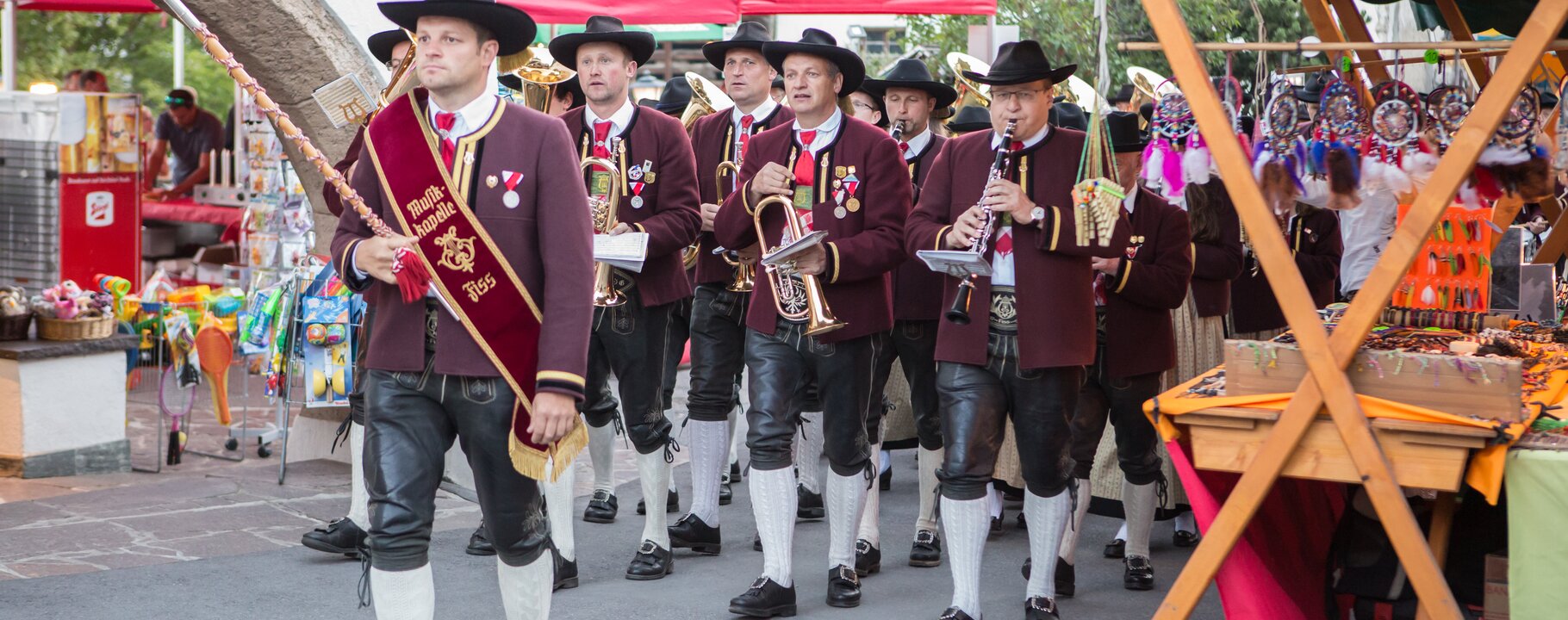 Musikanten in Tracht marschieren mit ihren Instrumenten durch den Marktbereich beim Fest am Brunnen in Fiss | © Serfaus-Fiss-Ladis Marketing GmbH | Andreas Kirschner