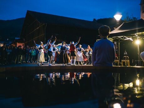 Menschen in traditionellen Trachten tanzen am Abend vor einer Menschenmenge unter freiem Himmel | © Serfaus-Fiss-Ladis Marketing GmbH | Andreas Kirschner