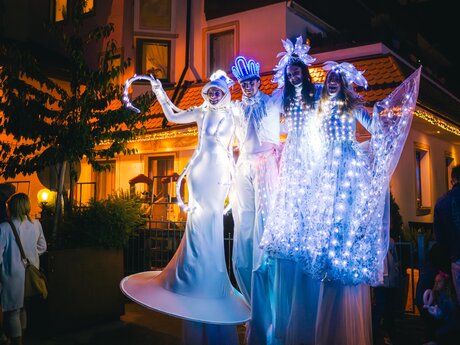 Stelzenläufer in leuchtenden Kostümen präsentieren eine Lichtershow bei Nacht vor beleuchtetem Gebäude | © Serfaus-Fiss-Ladis Marketing GmbH | Andreas Kirschner