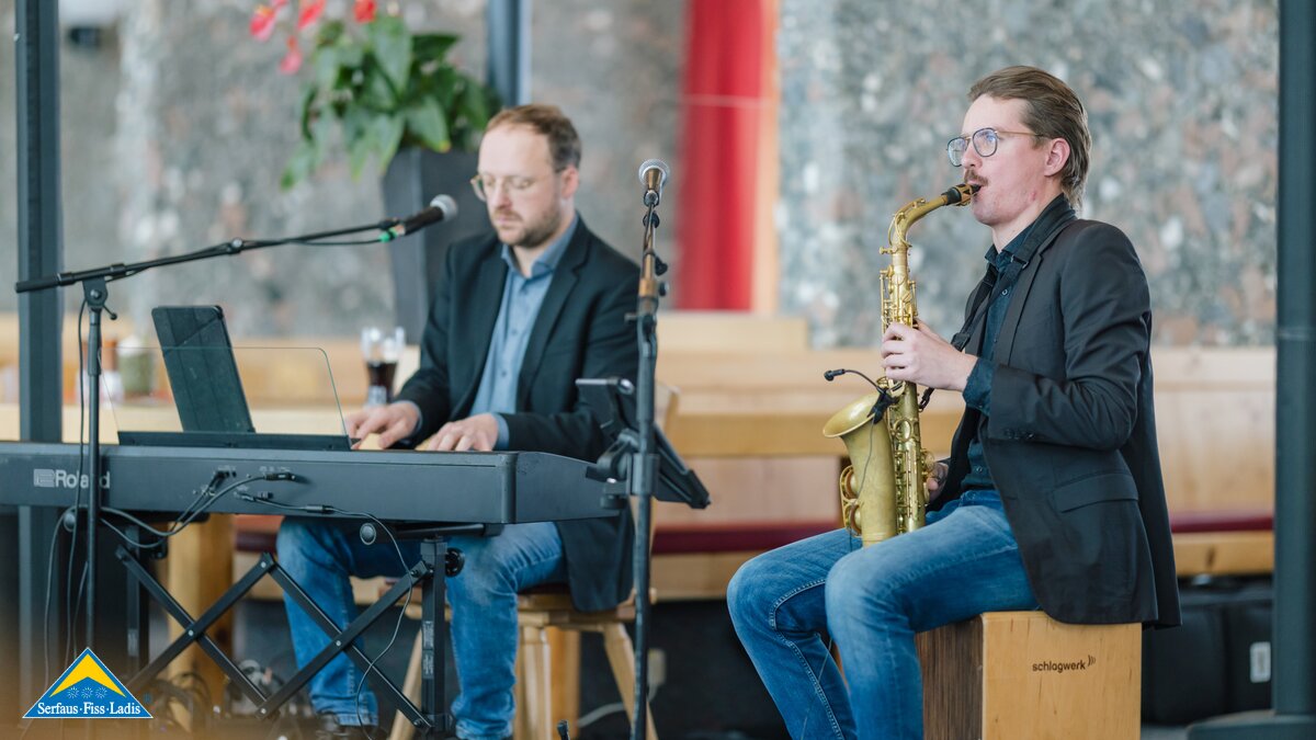 Zwei Musiker spielen Livemusik, einer am Saxophon, der andere am E-Piano, in einem stilvollen Innenraum | © Serfaus-Fiss-Ladis Marketing GmbH | Fabian Schirgi