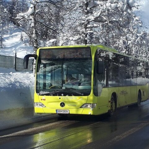 Gelber Skibus fährt auf schneebedeckter Straße durch eine winterliche Landschaft in Serfaus-Fiss-Ladis | © Serfaus-Fiss-Ladis Marketing GmbH