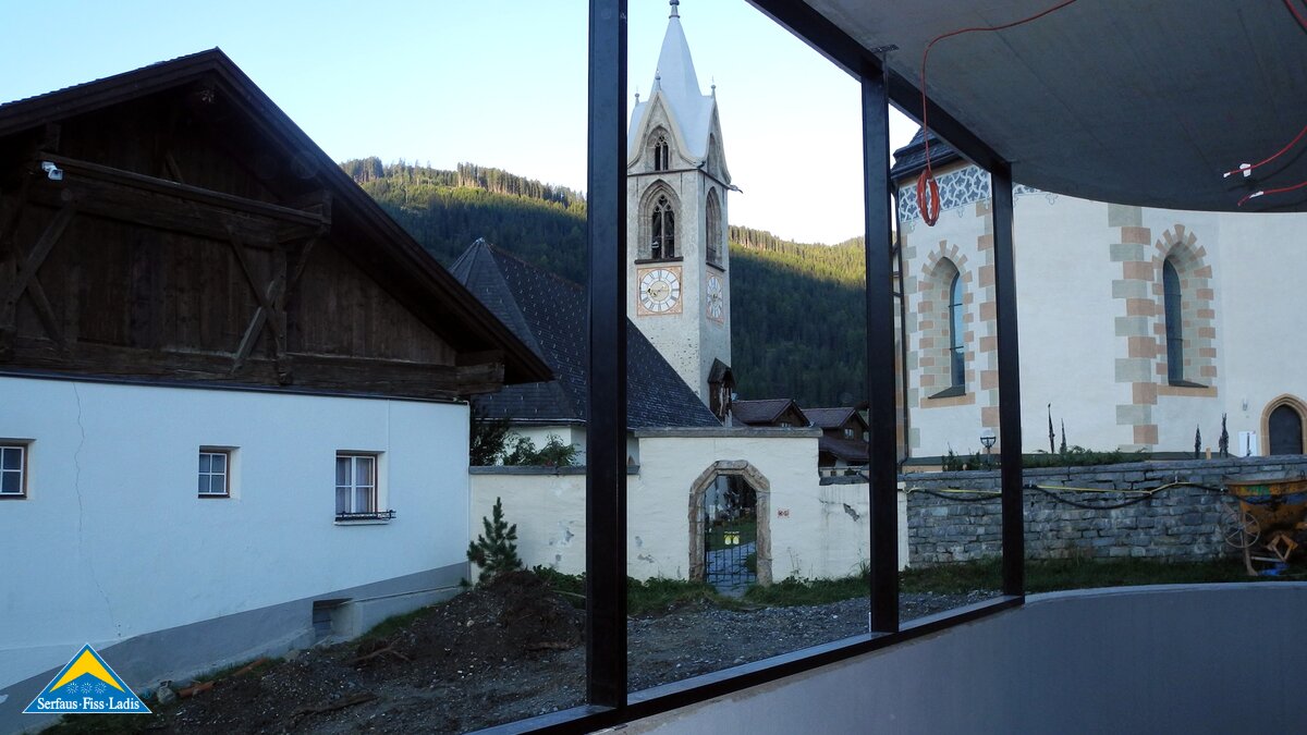 Blick auf die Kirche in Serfaus in Tirol durch die Glasfassade der U-Bahn Serfaus in Österreich | © Serfaus Fiss Ladis