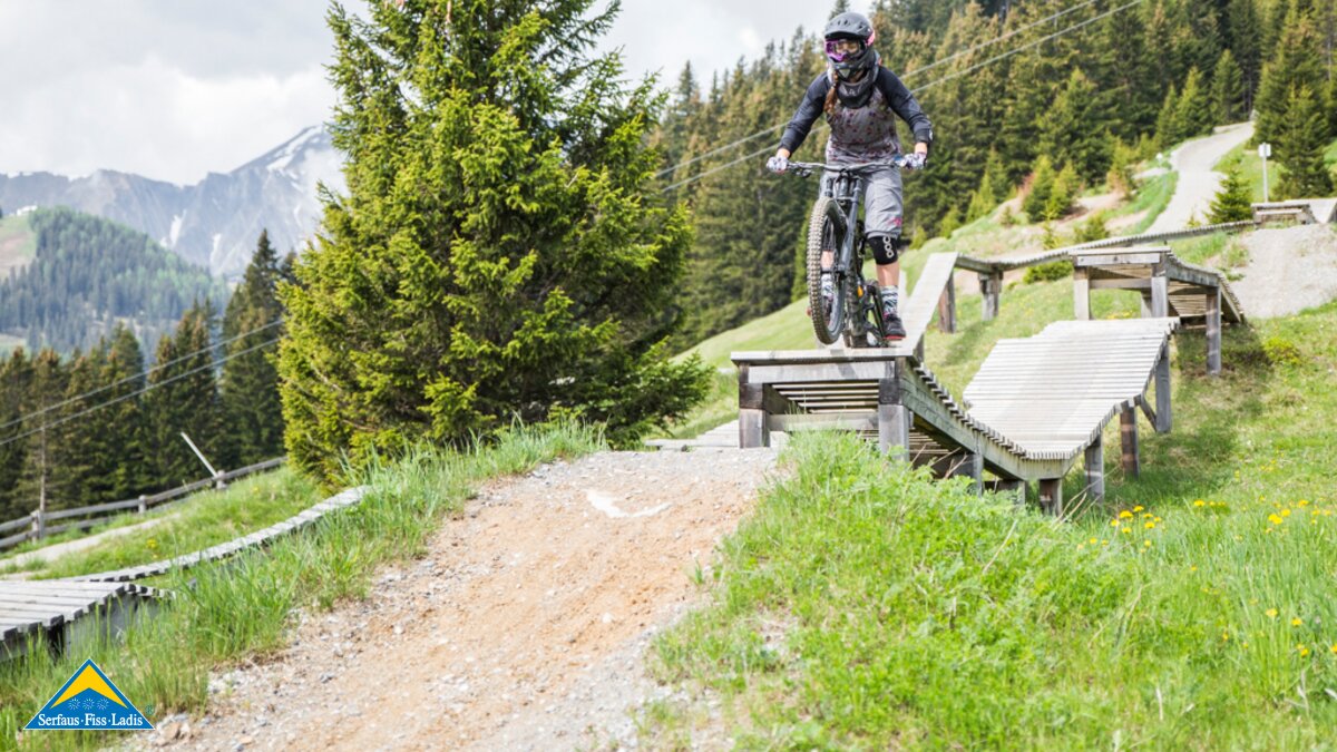 Celine Blochberger mit einem Sprung über ein Hindernis mit ihrem Downhillbike im Bikepark Serfaus-Fiss-Ladis in Tirol | © Socialweb
