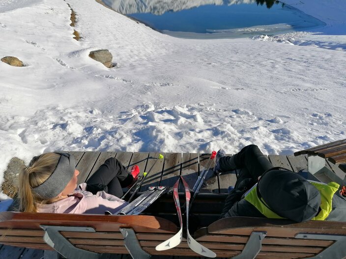Die Bank am Wolfsee in Serfaus-Fiss-Ladis lädt Winterwanderer und Langläufer zu einer Rast am wunderschönen Wolfsee, inmitten der Tiroler Bergwelt ein. | © Serfaus-Fiss-Ladis Marketing GmbH