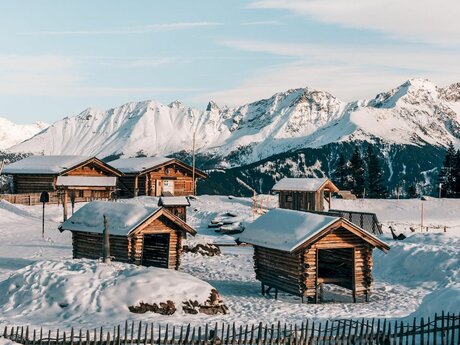Holzhütten auf dem zugefrorenen Högsee vor dem Bergrestaurant Seealm Hög im Winter Skigebiet Serfaus-Fiss-Ladis in Tirol | © sommertage.com