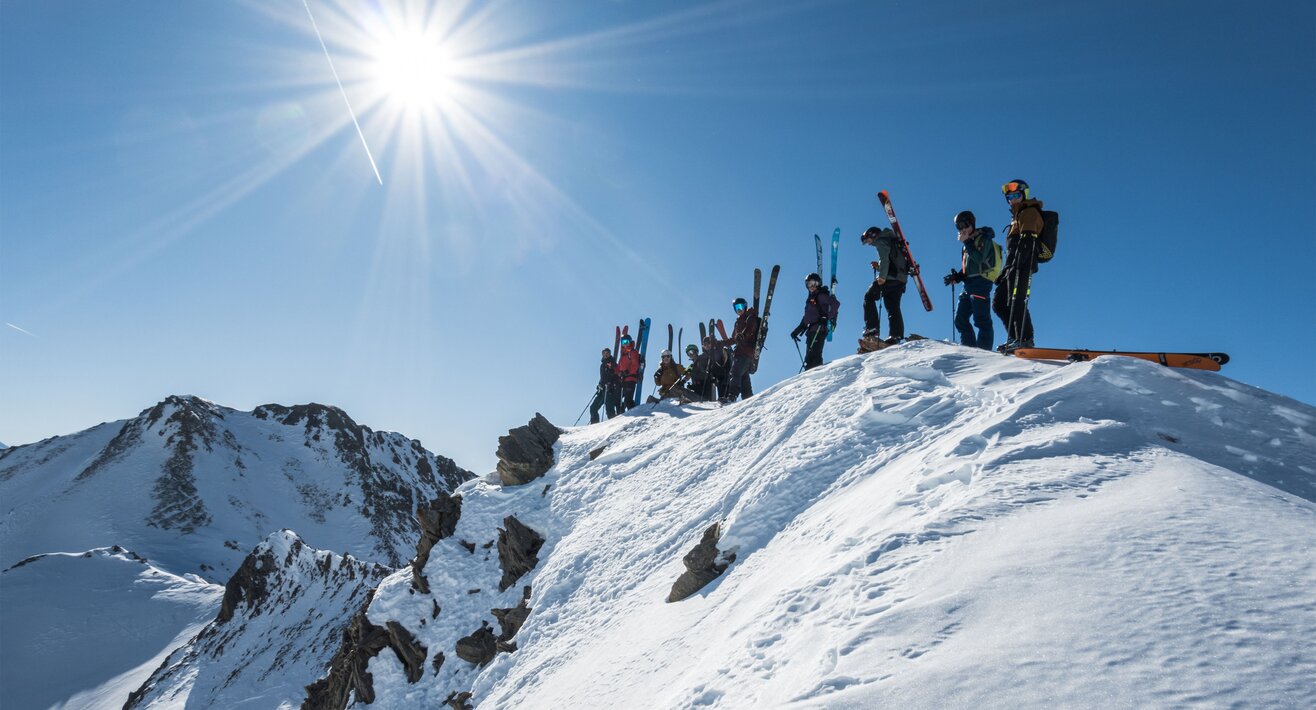  Gesamte Gruppe steht lächelnd und ausgerüstet vor einer Bergkulisse. | © Serfaus-Fiss-Ladis Marketing GmbH | Heli Düringer