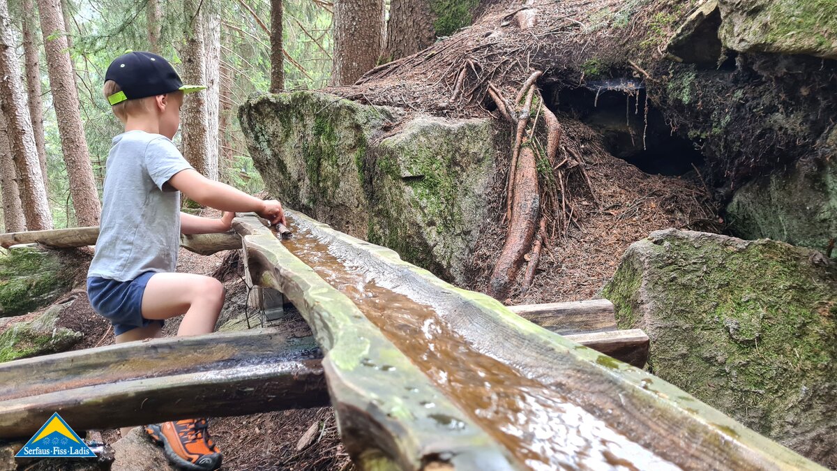 Kind spielt im Wald Wasserrinne Wasserwandersteig in Ladis Themenwege mit Kindern in Tirol Serfaus Fiss Ladis | © Serfaus-Fiss-Ladis Marketing GmbH