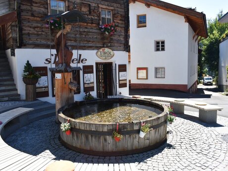Dorfbrunnen vor Geschäft sLadele Tirol genießen Serfaus Fiss Ladis  | © Serfaus-Fiss-Ladis Marketing GmbH