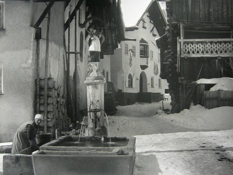 Untergassler Brunnen in Fiss Frau wäscht am Brunnen alte Fotografie Blog Dorfführungen Serfaus-Fiss-Ladis in Tirol | © Gemeindearchiv Fiss