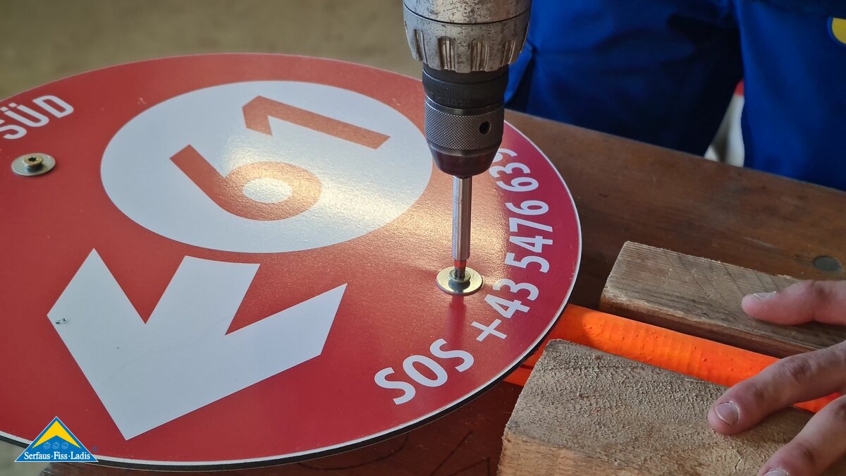 Anschrauben einer Pistennummer mit SOS-Nummer in der Familienregion Serfaus-Fiss-Ladis in Tirol | © Serfaus-Fiss-Ladis Marketing GmbH