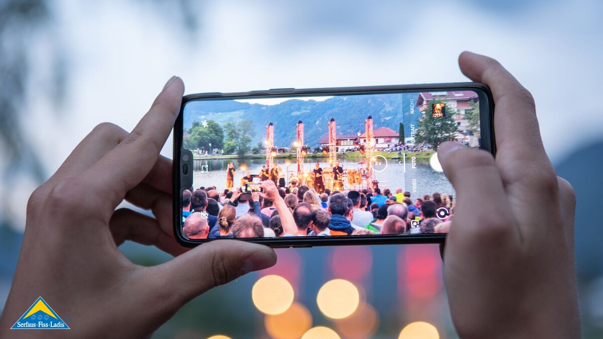 Konzert mit Handy festhalten Blick durchs Display auf die Bühne MOUNDS-Konzert Events Serfaus-Fiss-Ladis in Tirol | © Serfaus-Fiss-Ladis Marketing GmbH | Fabian Schirgi