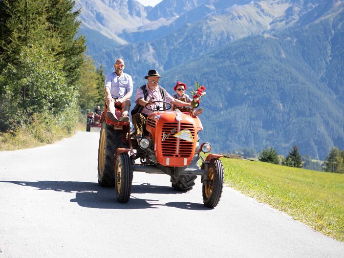 Bauern auf einem roten Traktor in Serfaus-Fiss-Ladis in Tirol Blogbeitrag Hintergrundbericht landwirtschaftliche Arbeiten | © Serfaus-Fiss-Ladis Marketing GmbH | Andreas Kirschner