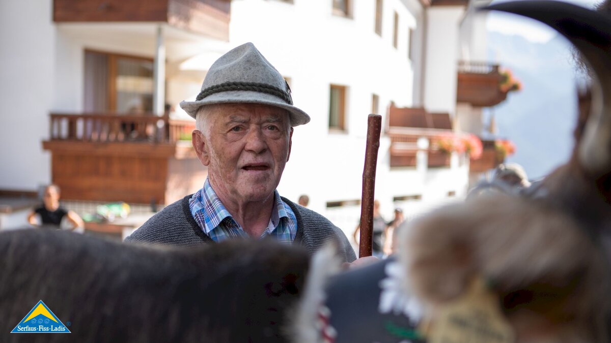Bauer mit Filzhut und Kuh im Vordergrund in Serfaus-Fiss-Ladis in Tirol | © Serfaus-Fiss-Ladis Marketing GmbH | Andreas Kirschner