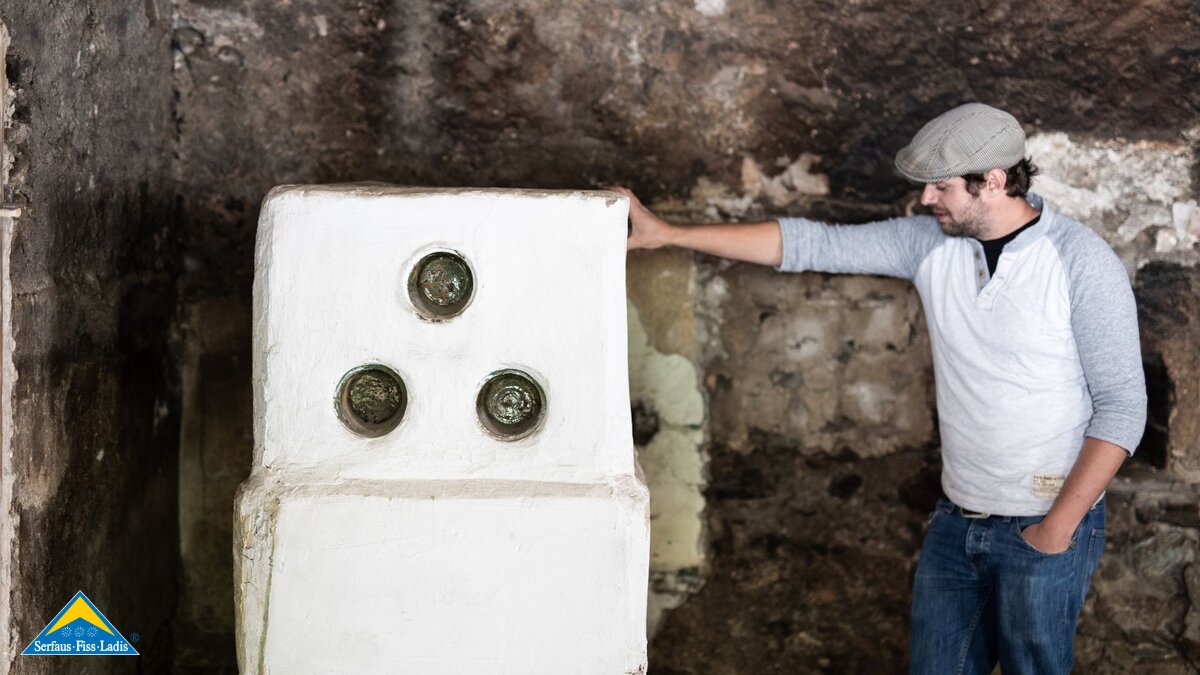 Simon Juen von Hanni's Haus vor einem alten Ofen Umbau denkmalgeschütztes Haus in Serfaus-Fiss-Ladis in Tirol | © Serfaus-Fiss-Ladis Marketing GmbH | Rene Raggl