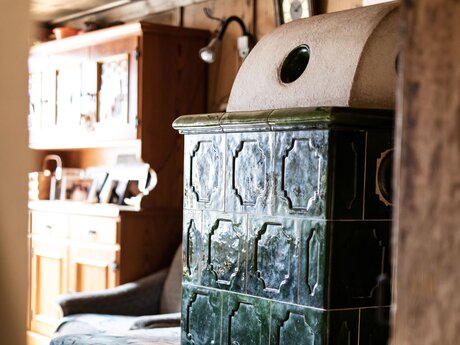 Alter Holzofen mit grünen Fliesen und Sitzbank in Serfaus-Fiss-Ladis in Tirol | © Serfaus-Fiss-Ladis Marketing GmbH | Rene Raggl