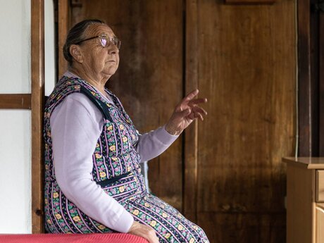 Frau sitzt auf einer Ofenbank Rosmarie Waldner aus Serfaus-Fiss-Ladis in Tirol | © Serfaus-Fiss-Ladis Marketing GmbH | Rene Raggl