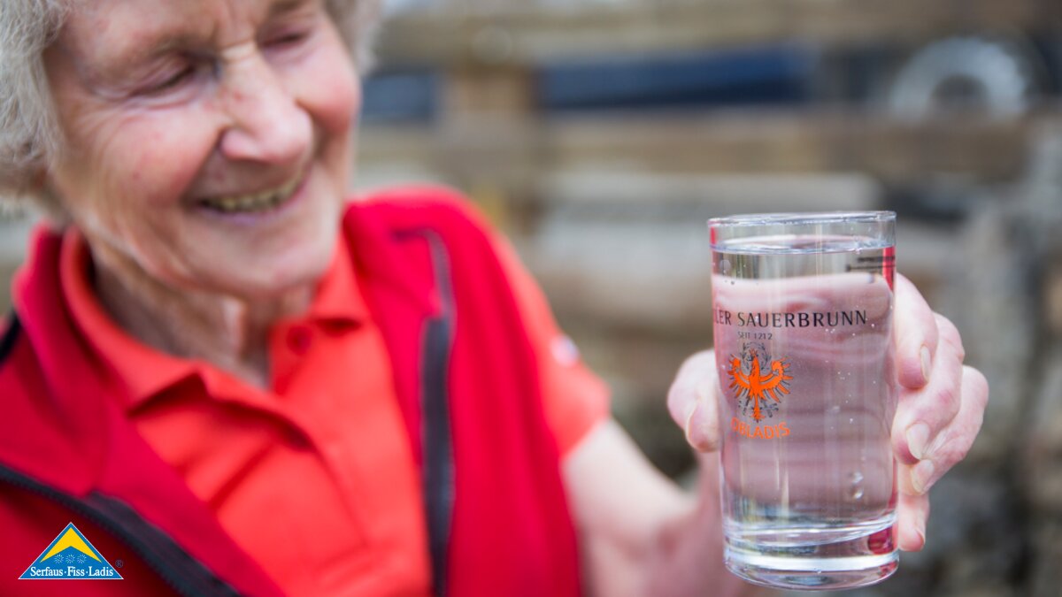 Seniorchefin Burgl mit einem Glas frischem Sauerbrunn aus Ladis in Tirol | © Socialweb