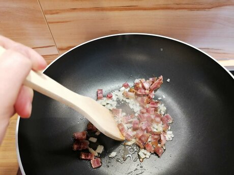Für das Tiroler Gröstl aus Serfaus-Fiss-Ladis müssen Speck und Zwiebel in Würfel geschnitten werden und in die heiße Pfanne gegeben werden | © Serfaus-Fiss-Ladis
