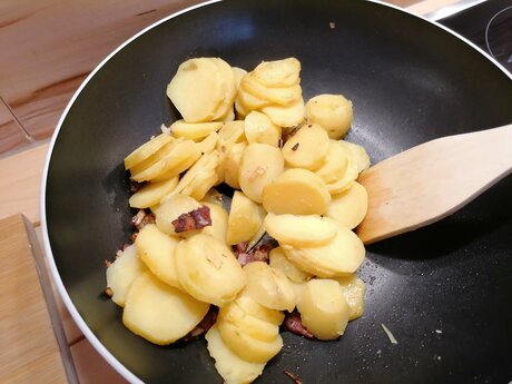 Für das Tiroler Gröstl aus Serfaus Fiss Ladis in Tirol gibt man Kartoffelscheiben, Speck und Zwiebel in die heiße Pfanne | © Serfaus-Fiss-Ladis