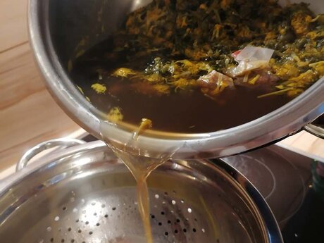 Das Löwenzahnwasser nach dem Rezept der Familienregion Serfaus-Fiss-Ladis in Tirol wird durch ein Sieb gegossen und anschließend wird Zucker eingerührt | © Serfaus-Fiss-Ladis