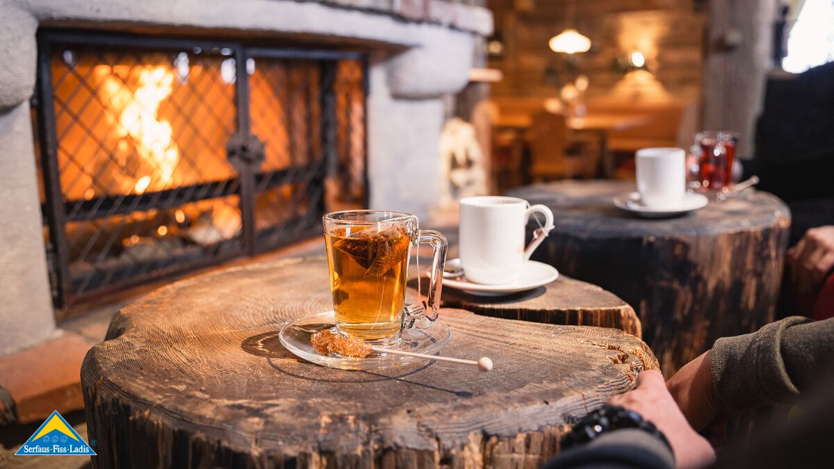 Tee trinken in einer Berghütte an einem offenen Kaminfeuer Zirbenhütte Serfaus-Fiss-Ladis in Tirol | © Fisser Bergbahnen GmbH | Manuel Pale