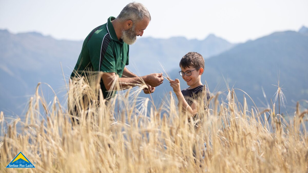Mann und Kind auf einem Getreidefeld in Serfaus-Fiss-Ladis in Tirol | © Serfaus-Fiss-Ladis Marketing GmbH | Andreas Kirschner