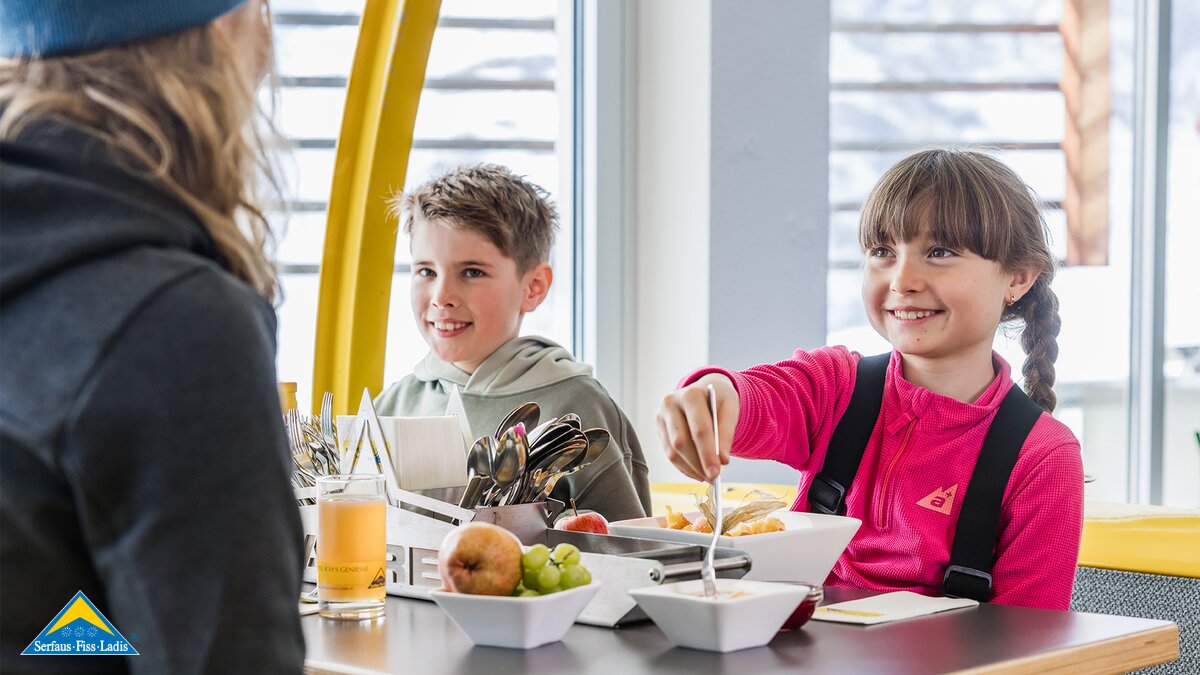 Skilehrerin der Skischule Serfaus sitzt am Esstisch mit ihrer Skischulgruppe Serfaus-Fiss-Ladis in Tirol | © Serfaus-Fiss-Ladis Marketing GmbH | Fabian Schirgi