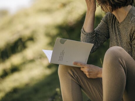 Autorin Monika Schmiderer beim Schreiben in der Natur mit Papierblock und Stift Interview im Blog Serfaus-Fiss-Ladis in Tirol | © Mike Rabensteiner
