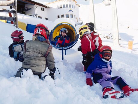 Skischulkinder rutschen von der Bergstation der Murmlibahn Kinderseilbahn auf Komperdell hinunter in das Übungsareal der Skischule Serfaus Kinderschneealm Familienregion Serfaus-Fiss-Ladis in Tirol | © Seilbahn Komperdell GmbH