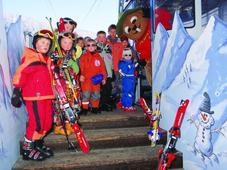 Einstieg Kinderseilbahn Murmlibahn in Serfaus Skischulkinder mit Maskottchen Murmli alte Pendelseilbahn Familienregion Serfaus-Fiss-Ladis in Tirol | © Seilbahn Komperdell GmbH