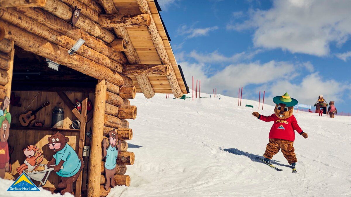 Maskottchen Murmli fährt zum Eingang des Förderbands in der Kinderschneealm in Serfaus Winterurlaub in der Familienregion Serfaus-Fiss-Ladis  | © Skischule Serfaus