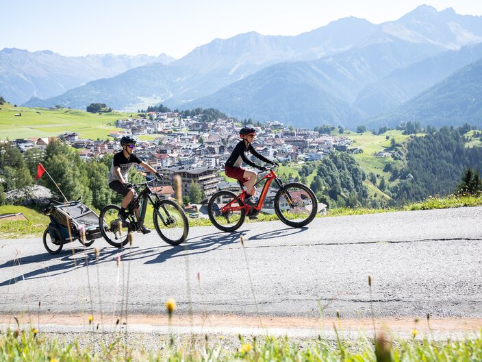 Blick auf Serfaus Familie macht einen E-Bikeausflug vom Dorf Serfaus zum Erlebnispark Hög beim Högsee | © Serfaus-Fiss-Ladis Marketing GmbH | Andreas Kirschner